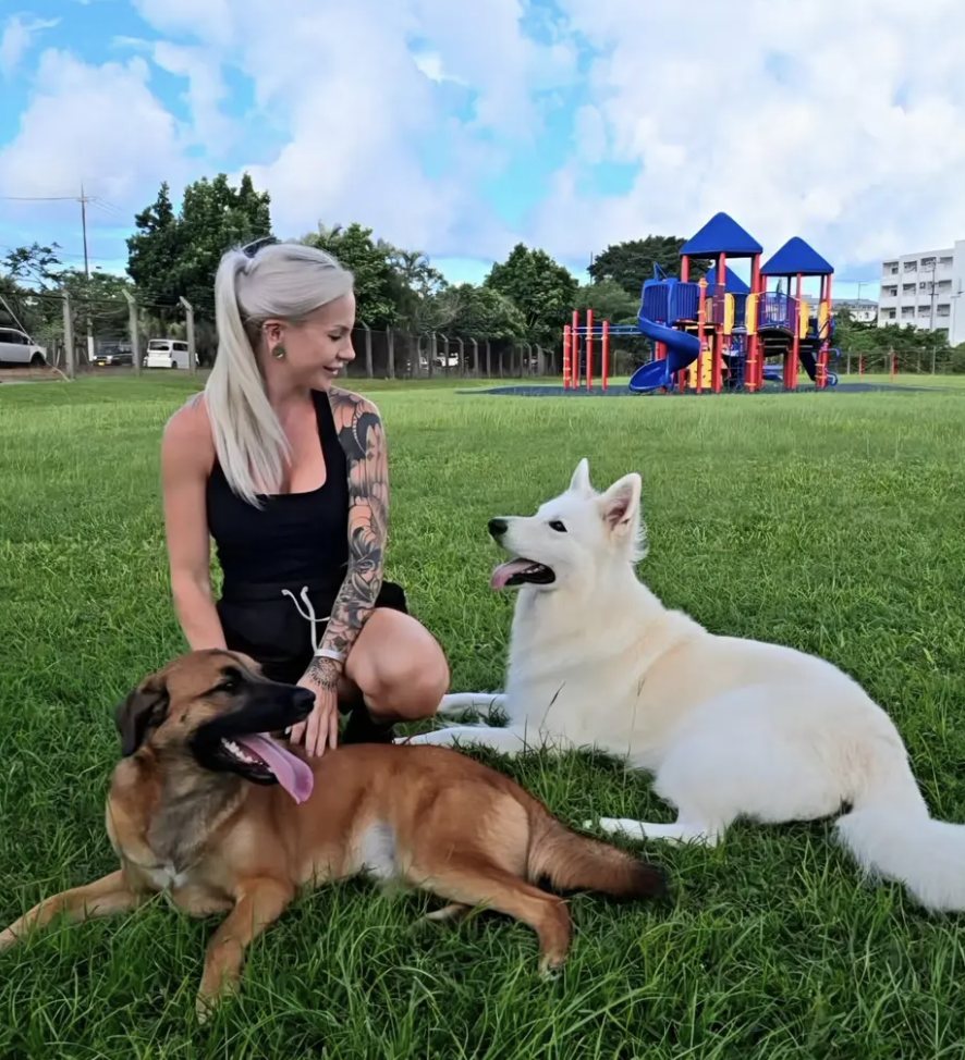 Nicole relaxing on the grass with two happy dogs